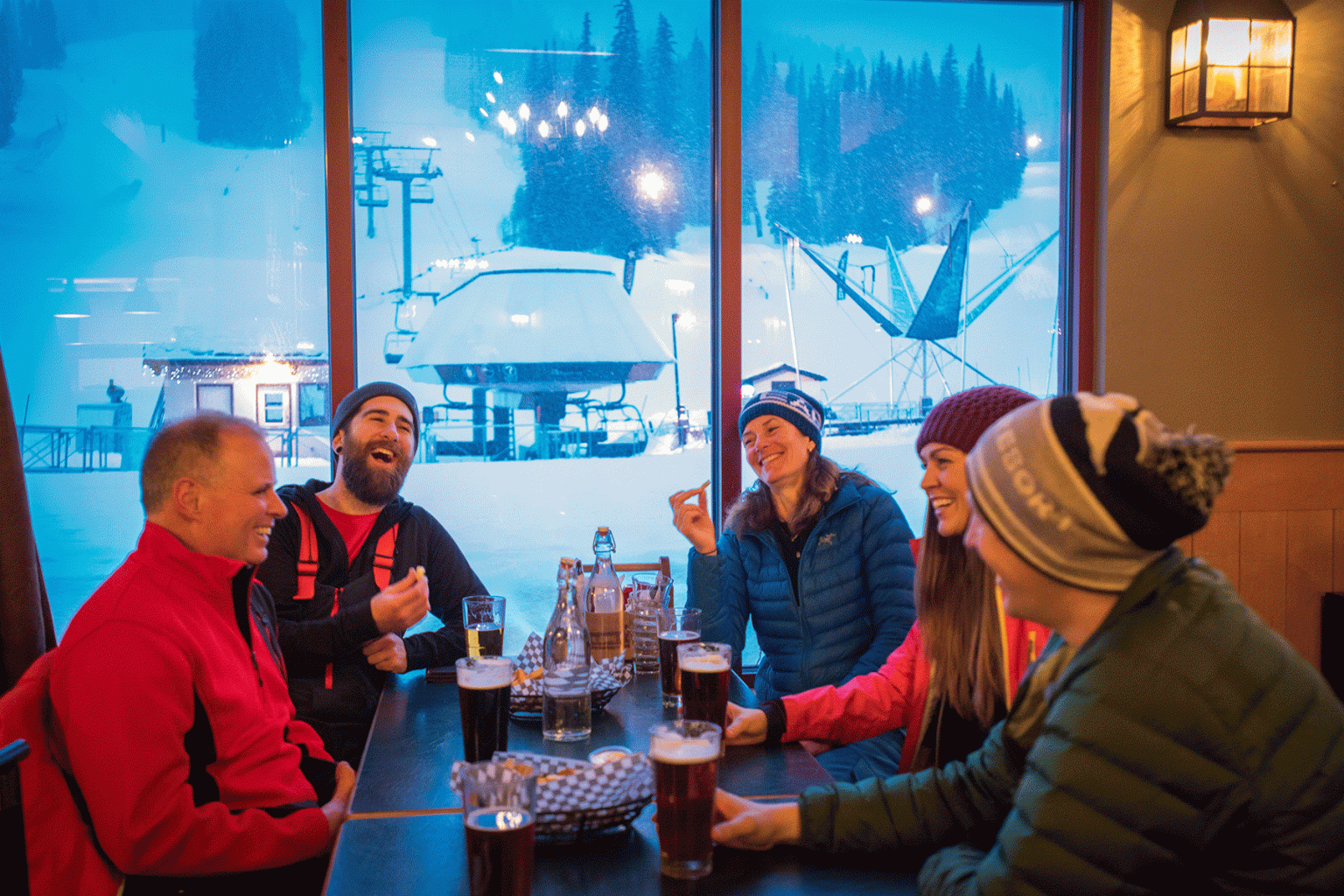 Five people sitting by a window with drinks