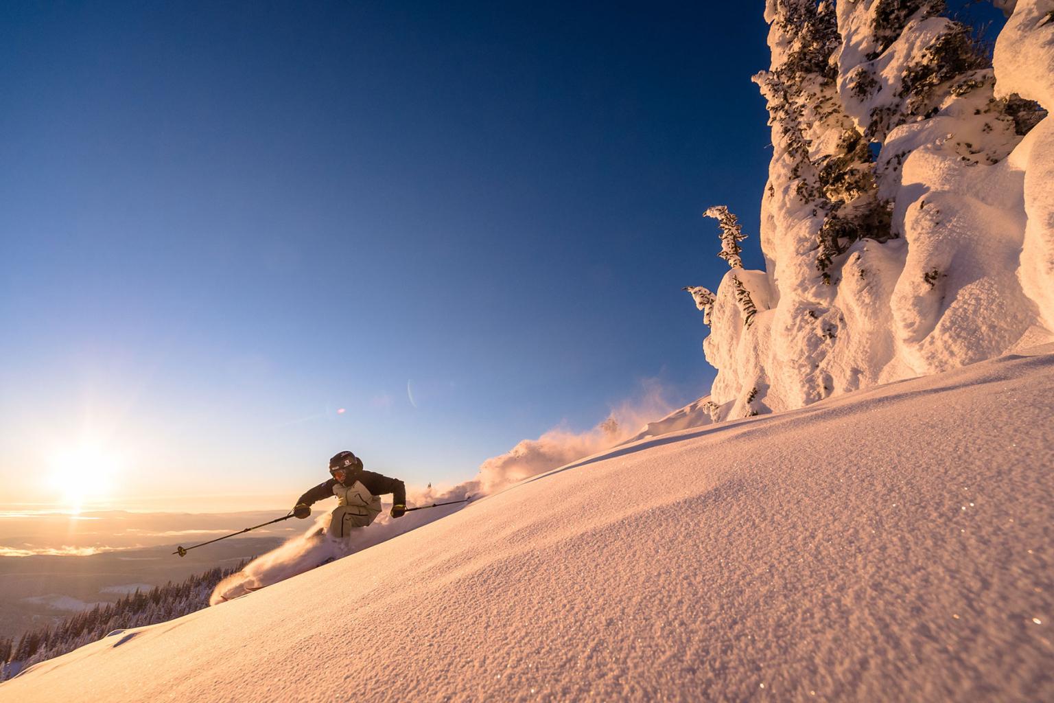 Two bikers going down a trail with lush greens around them and the village in the distance