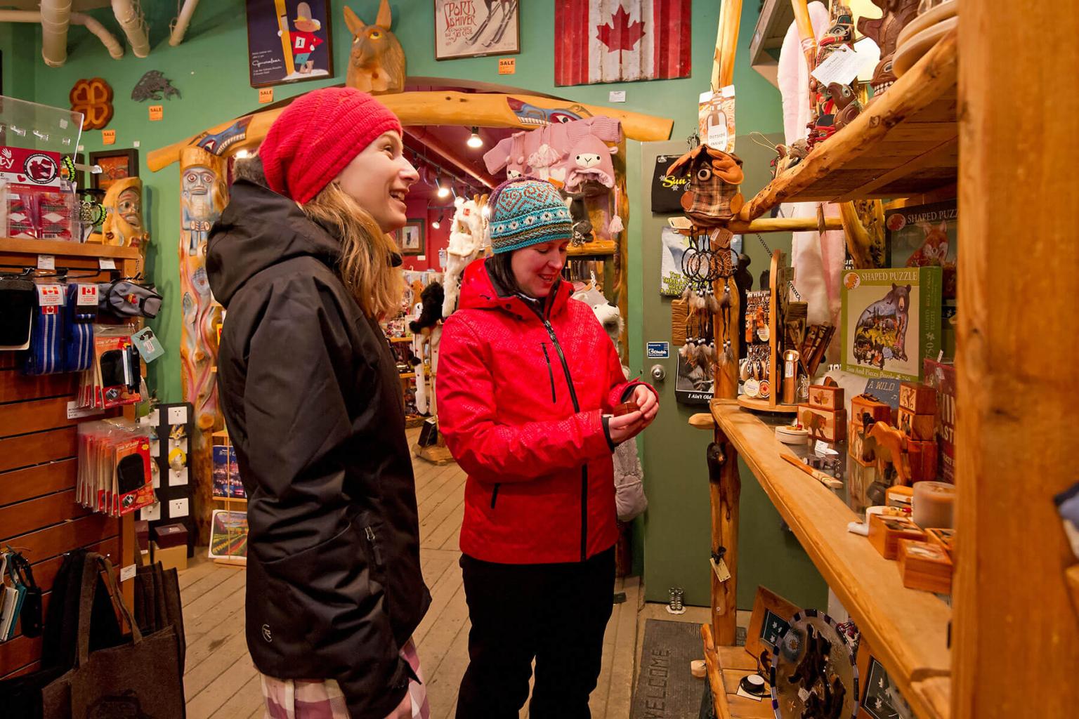 Two women in winterwear shopping for local gifts in Lone Wolf Gallery, Sun Peaks.