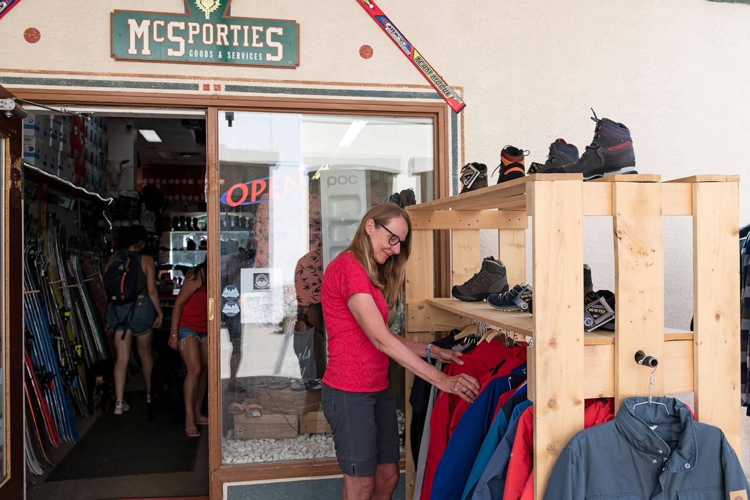 A woman looking at jackets outside of a store